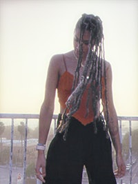 a woman with dreadlocks standing on a balcony